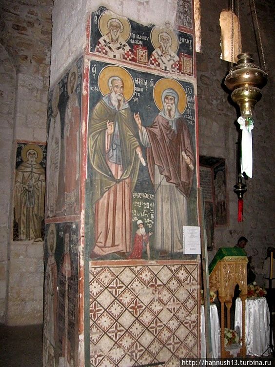 Слева – Максим Исповедник (582-662), справа – Иоанн Дамаскин (675-753), а между ними – Шота Руставели, принимавший участие в росписи монастыря, который запечатлел и свой портрет. Надпись на грузинском: “Расписавшему сей [храм] Шоте Руставели да простит Бог [грехи], аминь. Руставели”