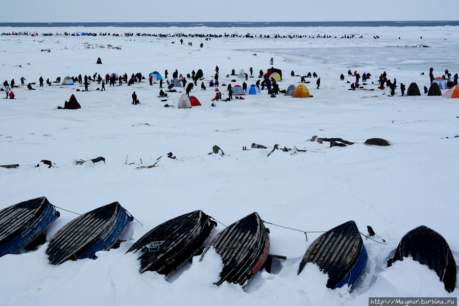 Дальная цепочка рыбаков  находится на кромке припая. Перед ними подвижное поле льда, а дальше на горизонте виднеется море. Южно-Сахалинск, Россия