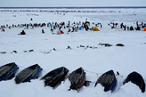 Дальная цепочка рыбаков  находится на кромке припая. Перед ними подвижное поле льда, а дальше на горизонте виднеется море.