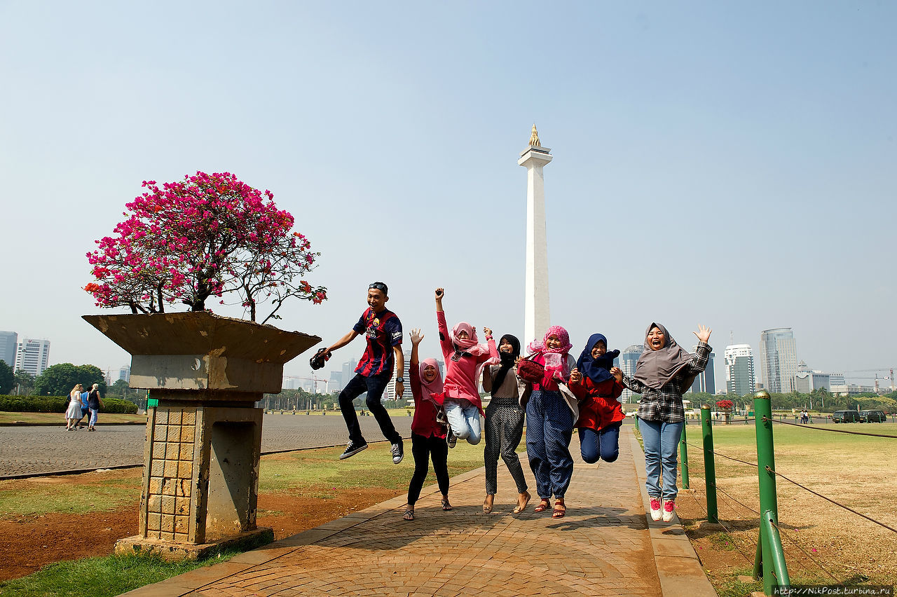Студенты на фоне The National Monument. Монумент большой. На верху — смотровая площадка и большой зал. В цокольном этаже — музей. Джакарта, Индонезия