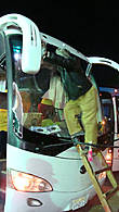 Мужик моет лобовое стекло автобуса с деревянной лестницы