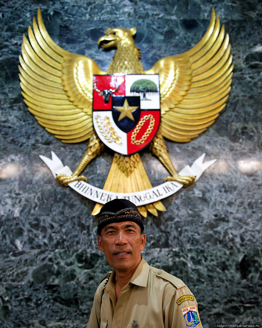 The National Monument.Гид на фоне герба Индонезии. Джакарта, Индонезия