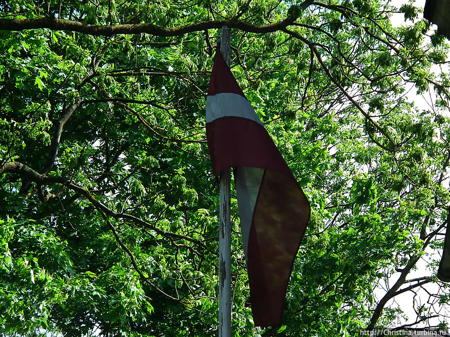 Среди развалин и хибар гордо реет латвийский флаг.