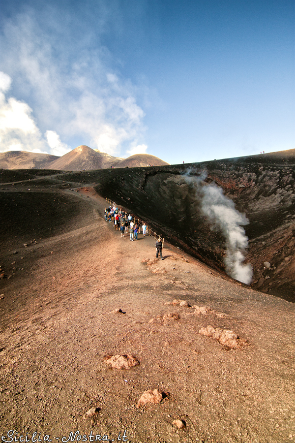 Группа туристов спокойно проходит мимо дымящего кратера.. они еще не знают, что через несколько минут соседний кратер загрохочет и выбросит облако пепла. Вулкан Этна Национальный Парк (3350м), Италия