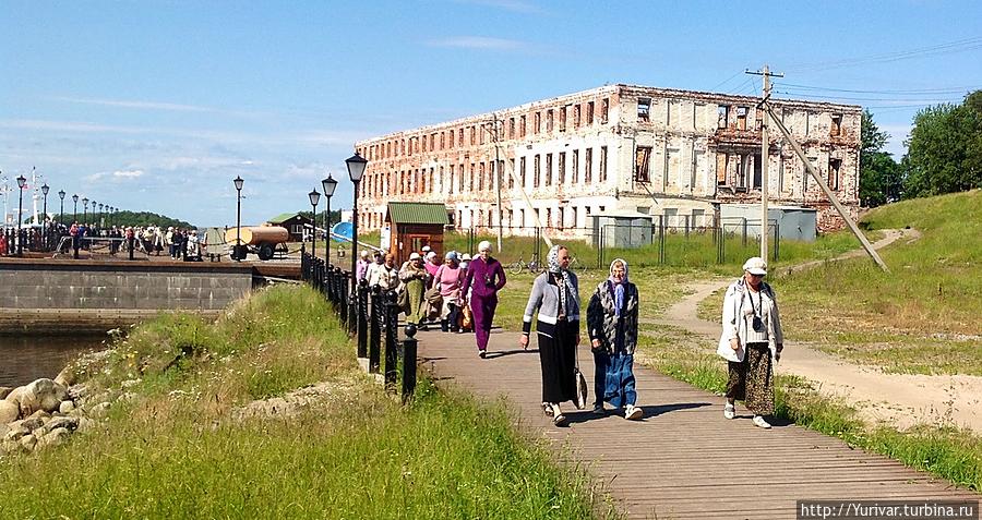 Паломники на экскурсии. На заднем плане — сгоревший дом гостеприимства постройки начала 20-го века. Соловецкие острова, Россия