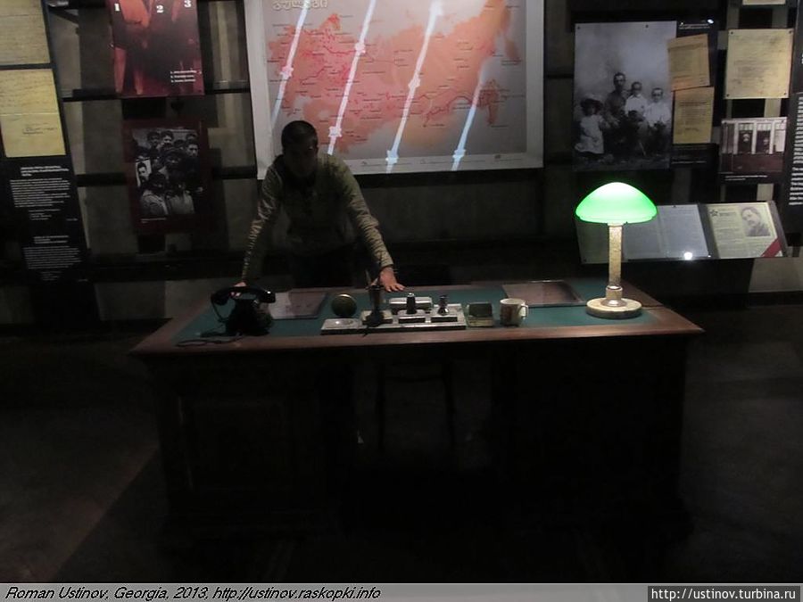 Р. Устинов за столом НКВДшника. На заднем плане — карта ГУЛАГа