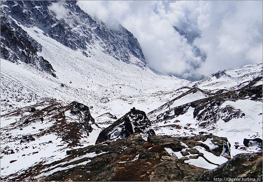 Теперь только вниз. Боже, что там впереди клубится. А теперь обратите внимание на левую часть снимка. Там видна малюсенькая фигурка туриста (под камушками), по которой можно понять, какого масштаба гора, уходящая куда-то вверх, в небо Госайкунд, Непал